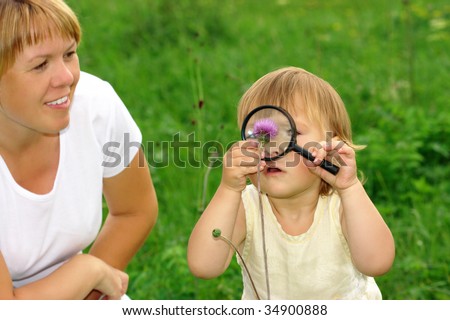 Cute little girl looking at flowers through magnifying glass