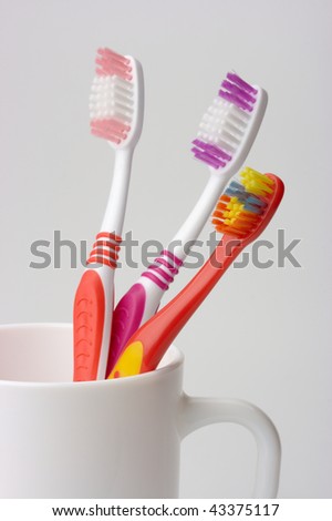 stock photo : Three toothbrushes in a cup - common toiletries, family concept