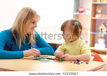 Teacher and cute little girl play with plasticine in preschool