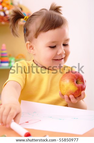 Cute little girl is going to eat apple in preschool