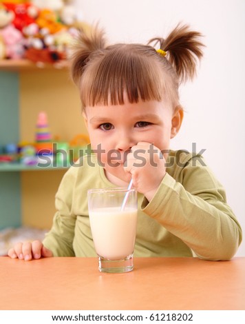 Happy little girl drinks milk in preschool