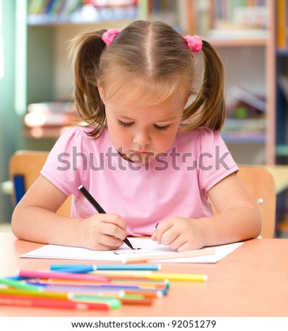 Cute little girl is drawing with felt-tip pen in preschool