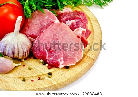 Cuts of meat, garlic, tomato, parsley and dill on a round wooden board isolated on white background