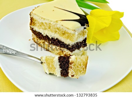 Piece of cake with a fork and yellow tulips on a white plate and a yellow napkin isolated on white background