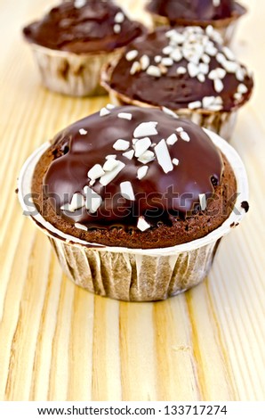Four cupcakes chocolate with white chocolate crumbs on a wooden board