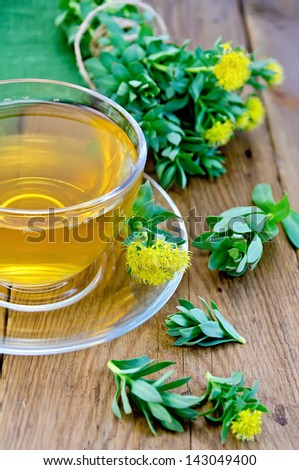 Healing herbal tea in a glass cup, flowers Rhodiola rosea, green napkin on a background of wooden boards