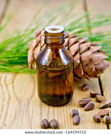 Cedar oil in a bottle, cedar cone, cedar nuts on the background of wooden boards