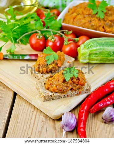 Sandwich with squash caviar and parsley, garlic, tomatoes, peppers, vegetable oil on the background of wooden boards