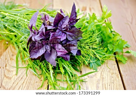 Beam of purple basil, parsley, tarragon and dill on a wooden boards background