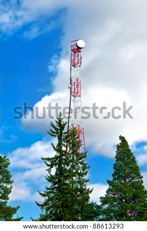 Communications tower, green trees against the blue sky and white clouds