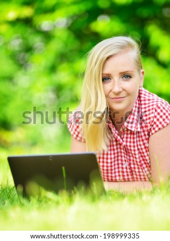 Young attractive woman lying on lawn with laptop.  MANY OTHER PHOTOS FROM THIS SERIES IN MY PORTFOLIO.