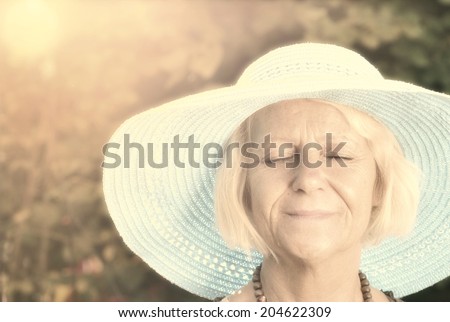 Mature woman in blue hat in garden. Vintage Style.