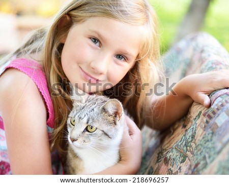 Little girl with cat. Outdoors.
