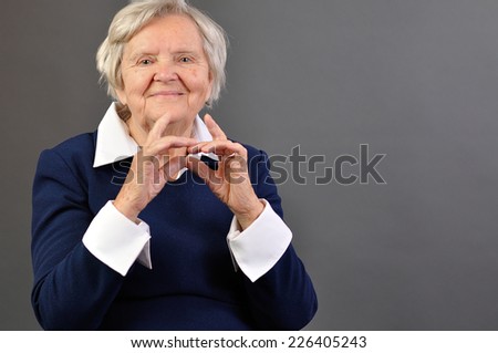 Senior happy woman with grey hairs against grey background.