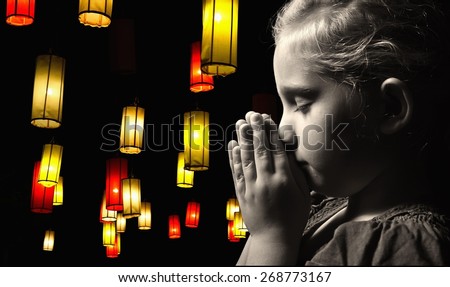Praying child On a black background full of lanterns. MANY OTHER PHOTOS FROM THIS SERIES IN MY PORTFOLIO.