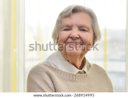 Senior happy woman in her home with window on background. MANY OTHER PHOTOS FROM THIS SERIES IN MY PORTFOLIO.