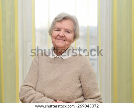 Senior happy woman in her home with window on background. MANY OTHER PHOTOS FROM THIS SERIES IN MY PORTFOLIO.