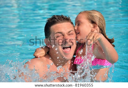 Father and daughter playing in the pool.