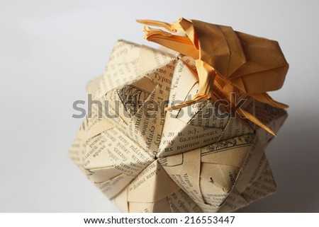 Orange origami bug climbing over sphere covered with cyrillic letters