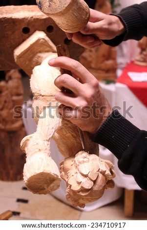 Wood carver\'s hands sculpting a wooden angel in workshop