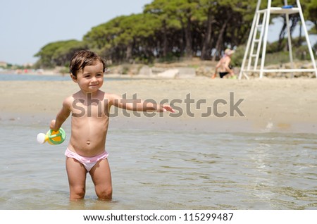 Happy Baby playing with a bucket of water at the beach, Italy