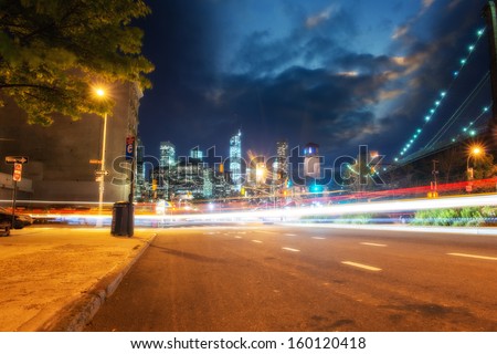 Skyline of Manhattan at sunset from Brooklyn streets with car light trails, New York.