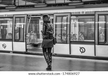 PARIS - NOV 28, 2012: Young girl awaits the train in Paris Metro station. Paris Metro is the 2nd largest underground system worldwide by number of stations (300). Processed in black and white