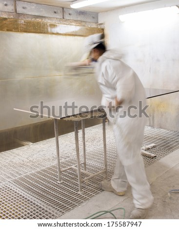 Worker in industrial environment smoothing wood board, blurred movement.