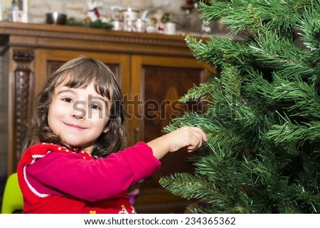 Girl enjoying Christmas tree at home. Joy and holiday concept.