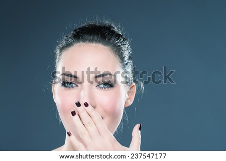 Secret woman saying be quiet. Girl with hand in front of mouth. shut up.In red blouse. Grey background. Studio shot.