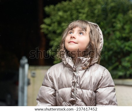 Cute baby girl looking up outdoor with happy and satisfied face expression.
