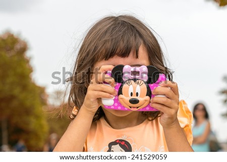 PARIS, FRANCE - JULY 20, 2014: Baby girl enjoy city view with her toy camera. More than 30 million tourists visit Paris every year.