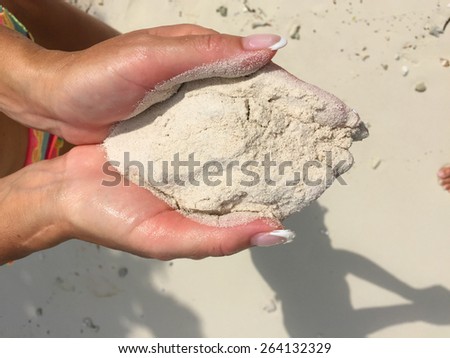 Woman hands holding sand on the beach.