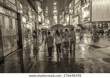 NEW YORK CITY - JUNE 13, 2013: People walk on a rainy night in Times Square. The city attracts more than 50 million people annually.
