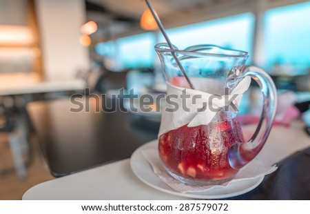 Large jar of sangria with red wine, oranges and ice served in a restaurant.