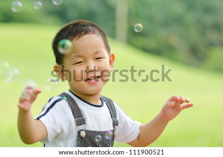 happy asian kid playing soap bubble ,candid