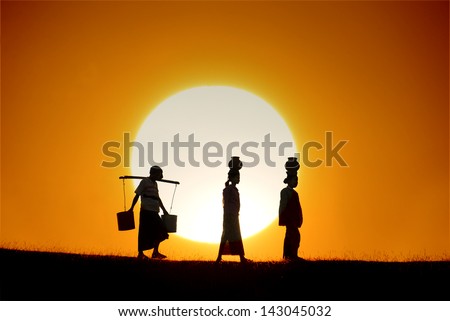 silhouette of traditional asian farmer coming back from a harvest with beautiful sunset