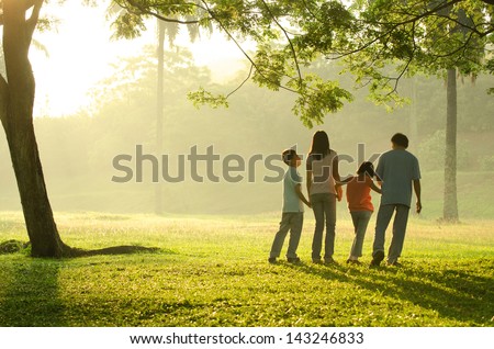 silhouette of a family walking in the park during a beautiful sunrise, backlight