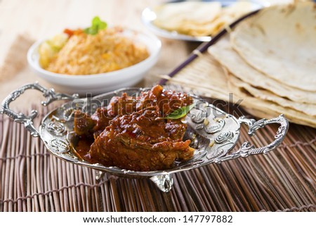 Butter chicken curry with basmati rice and various indian foods at background