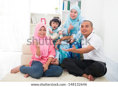 malay family watching television enjoying quality time