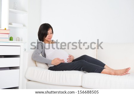 asian pregnant mother sitting on couch