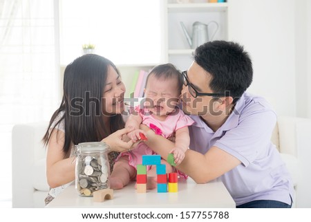 crying asian baby being comforted by chinese parents