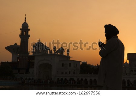 Silhouette of praying sikh man at golden temple of Amritsar, India