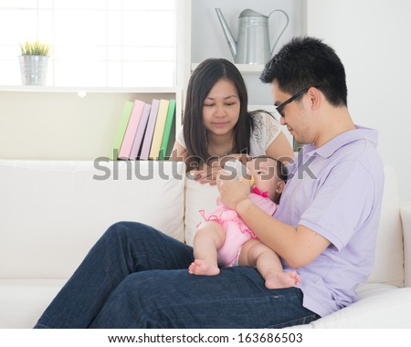 chinese asian parents feeding baby boy at home