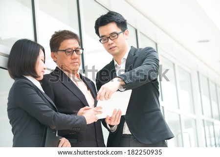 asian business team reporting to senior ceo with office background