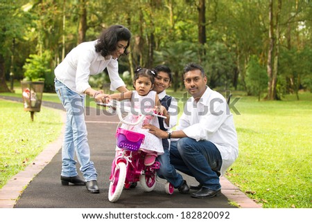 indian family teaching their kids cycling in the outdoor park