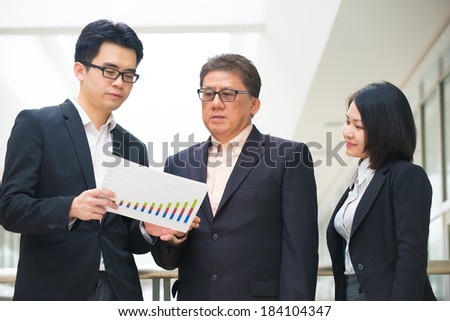 asian business team reporting to senior ceo with office background