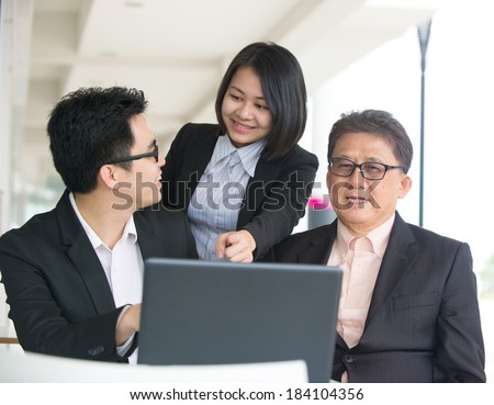 Group of asian business people gathered together at a table discussing an interesting idea in the cafe