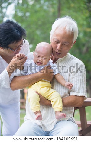 asian baby crying while being comforted by grandparents