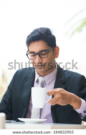 young indian business man on laptop and coffee at a cafe
